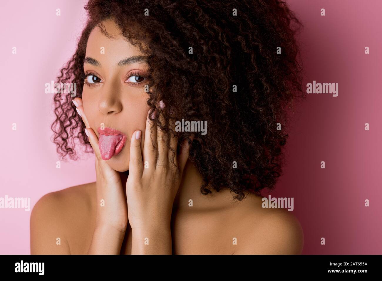 portrait of funny african american girl sticking tongue out on pink ...