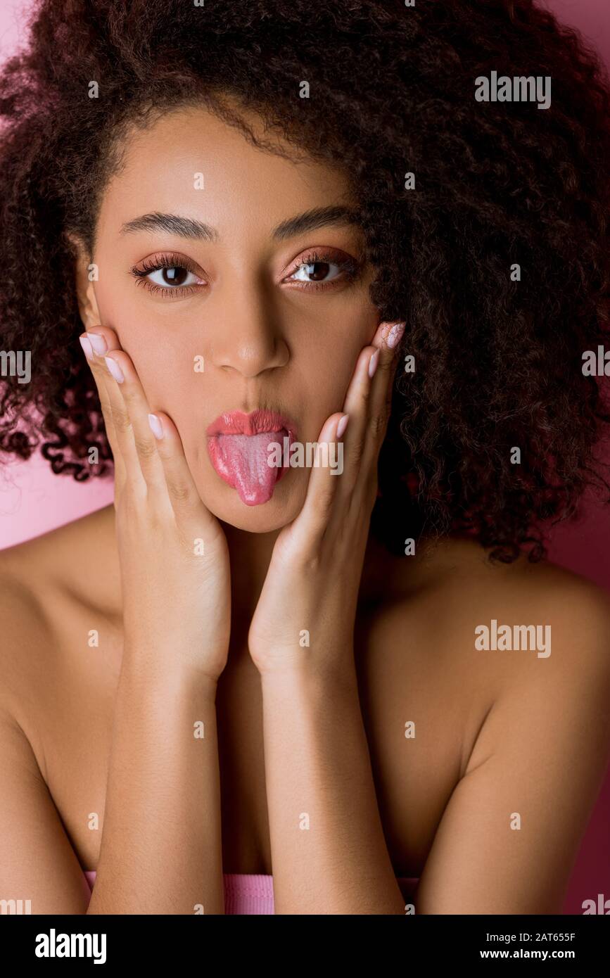 portrait of happy curly african american girl sticking tongue out on ...