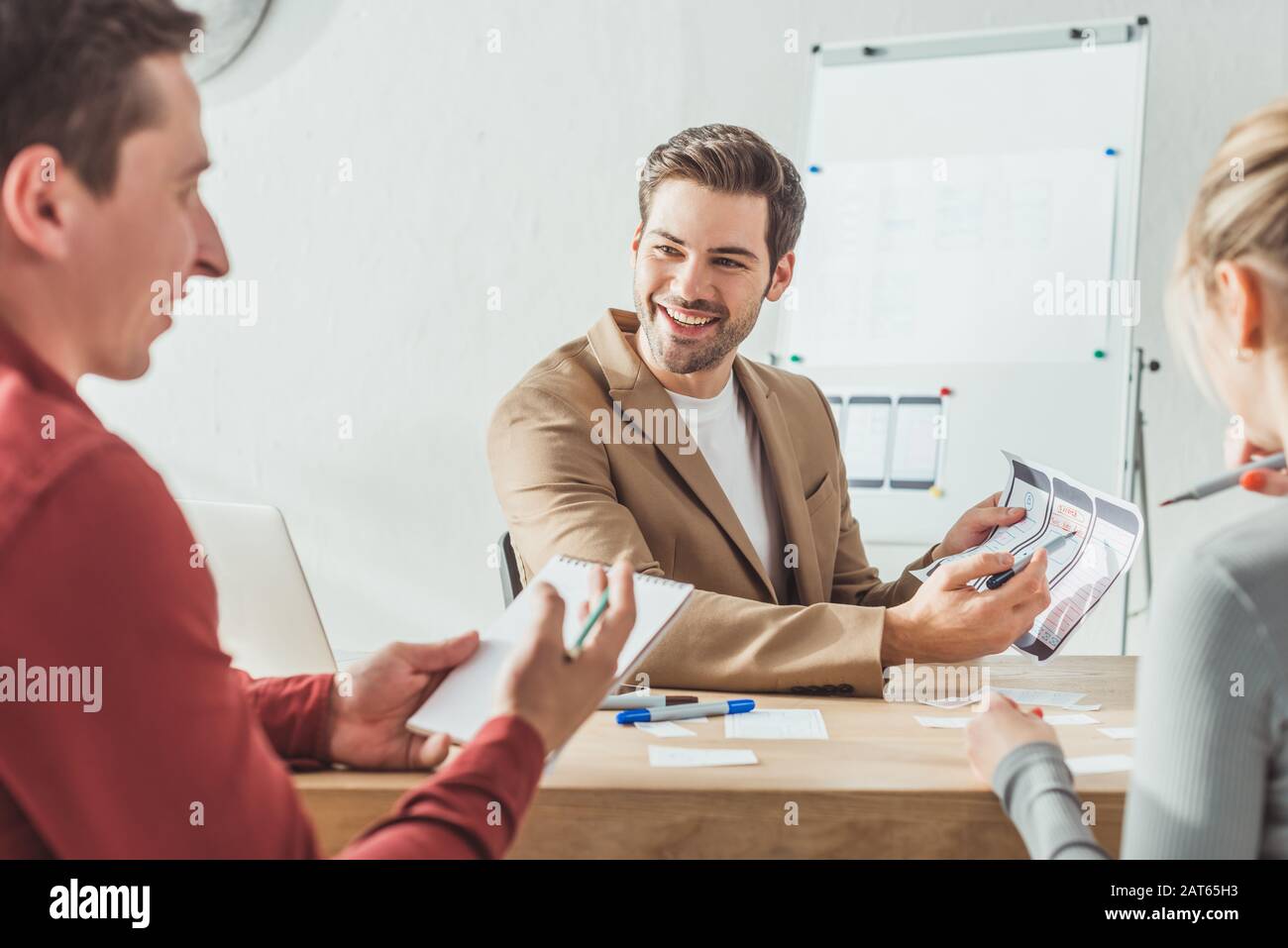 Selective focus of smiling designers developing mobile app interface in designer studio Stock Photo