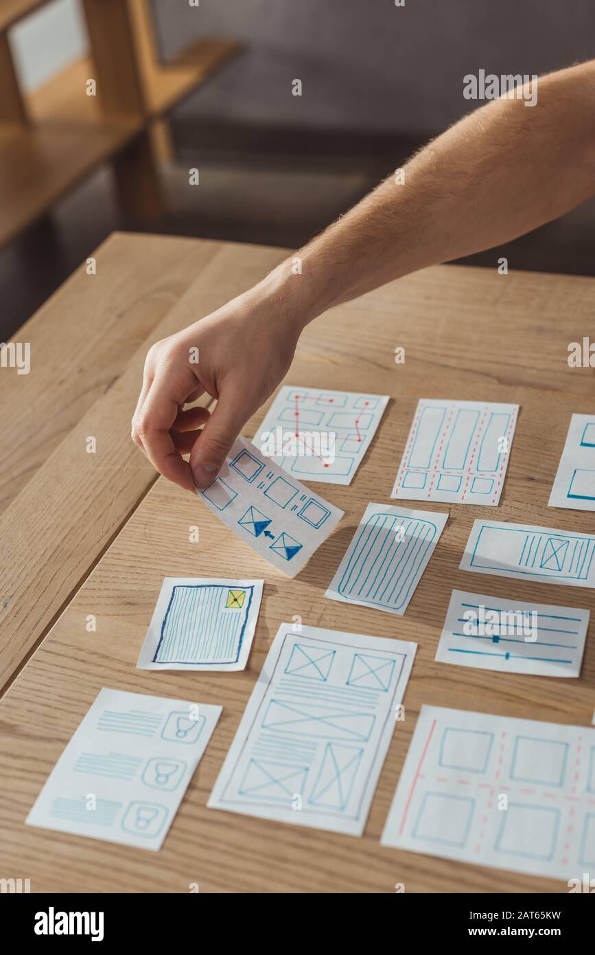 Cropped view of ux developer working with app sketches on table Stock ...