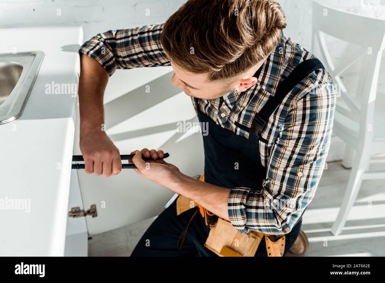 installer holding slip joint pliers while working near kitchen