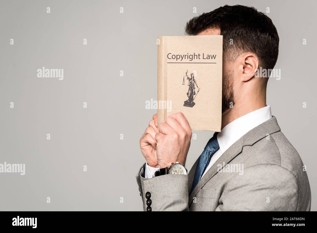 side view of lawyer obscuring face with copyright law book isolated on