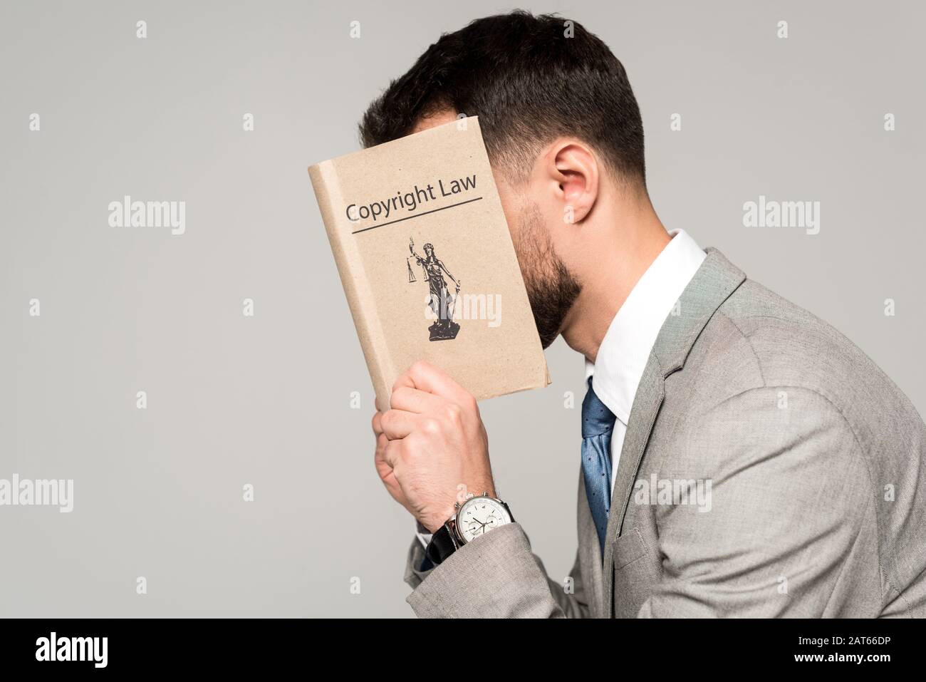side view of lawyer obscuring face with copyright law book isolated on