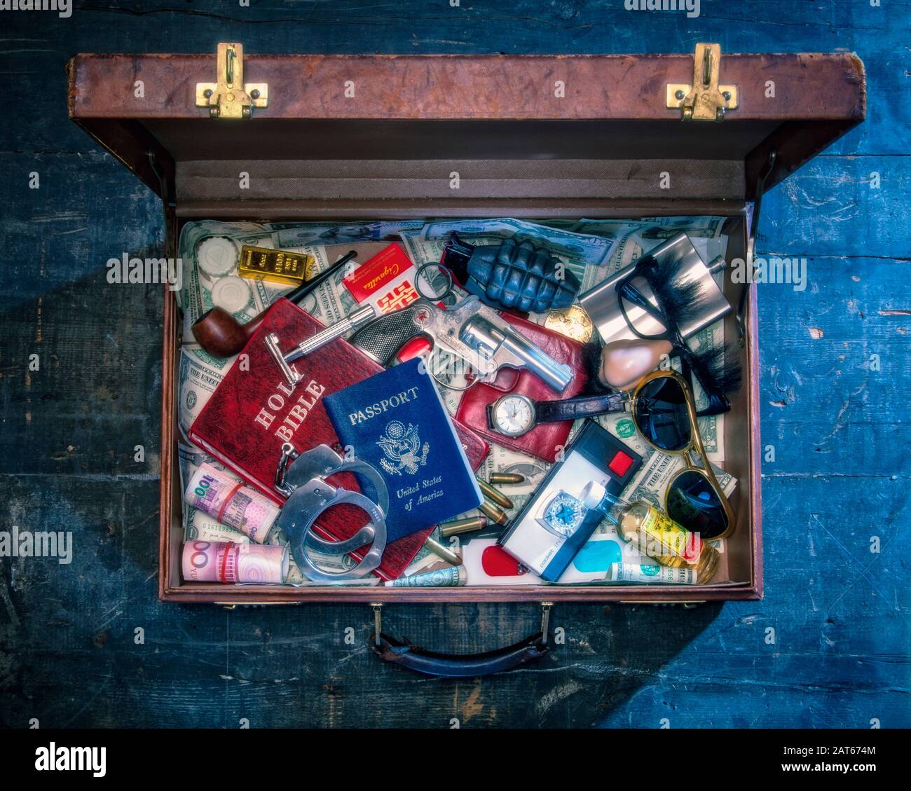An overhead view of an old style leather briefcase filled with random and dangerous travel items Stock Photo