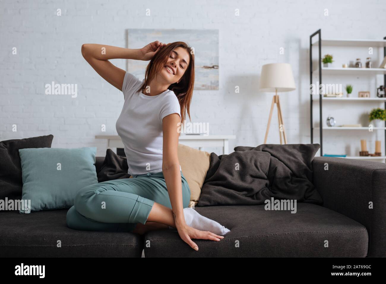 young smiling woman with closed eyes chilling on sofa in living room ...