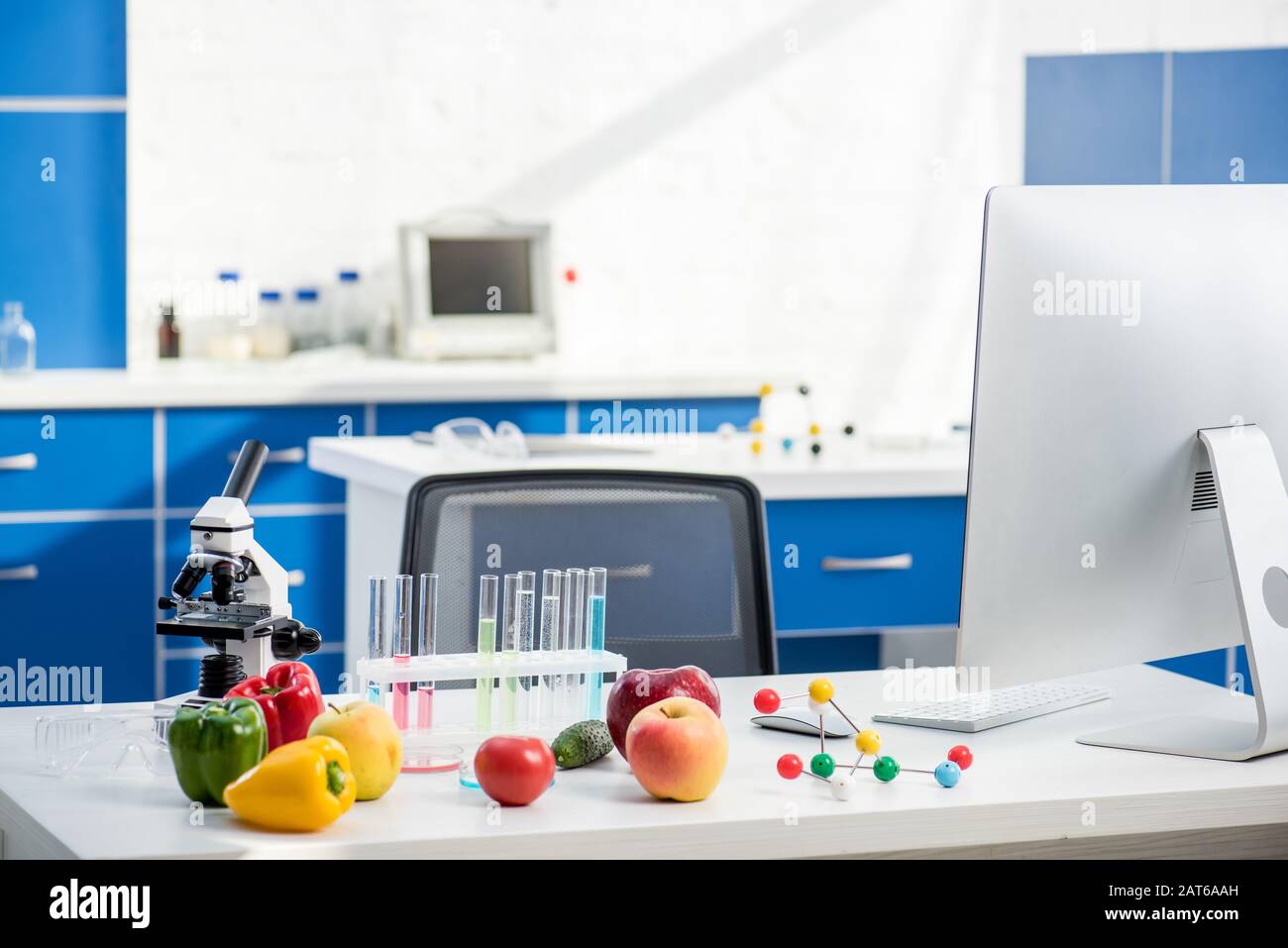 microscope, fruit, vegetables, test tubes and computer on table in lab ...