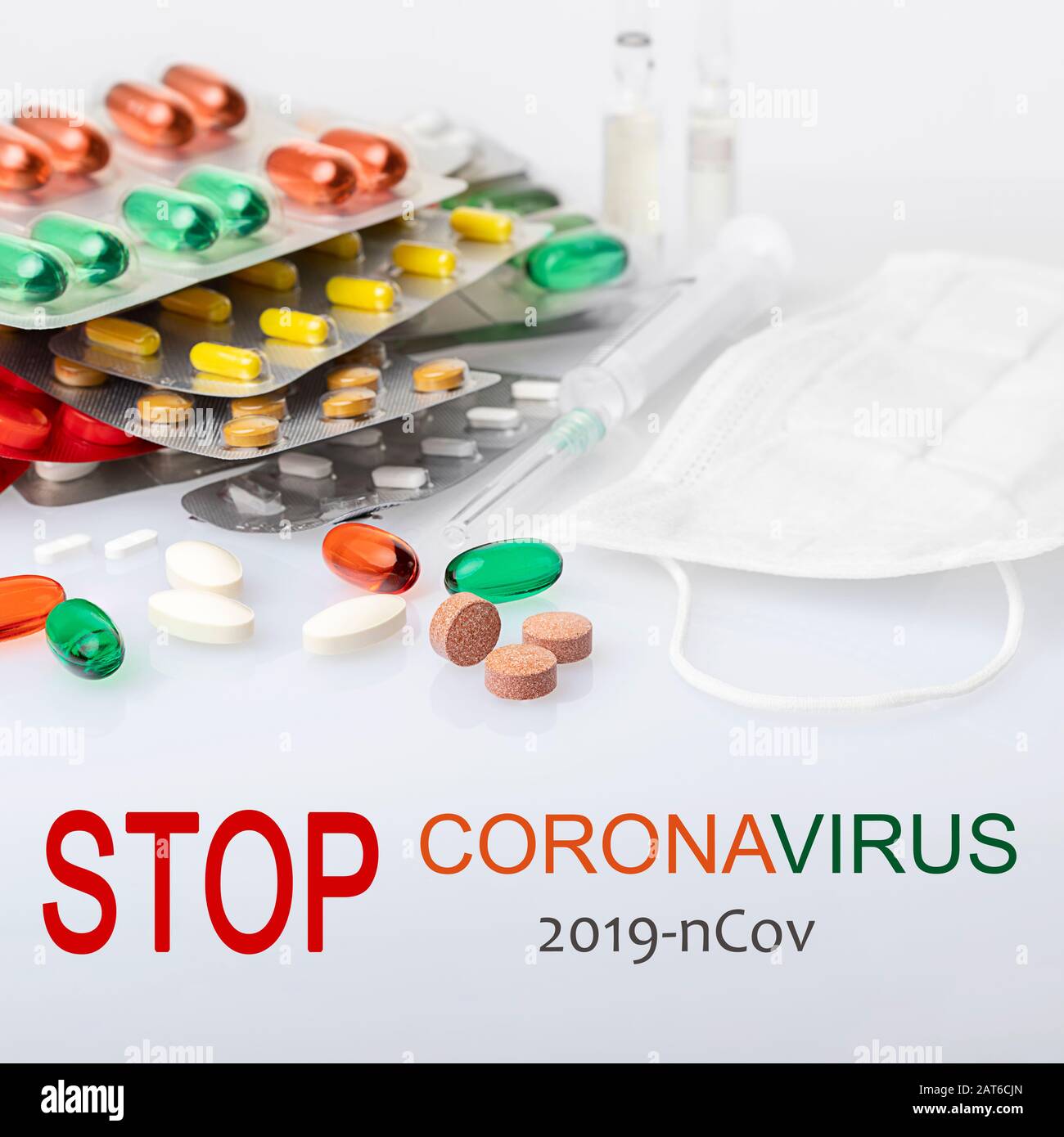 Coronavirus treatment concept. Assorted pharmaceutical medicine pills, tablets, capsules, surgical mask protective mask, ampoules. and plastic syringe Stock Photo