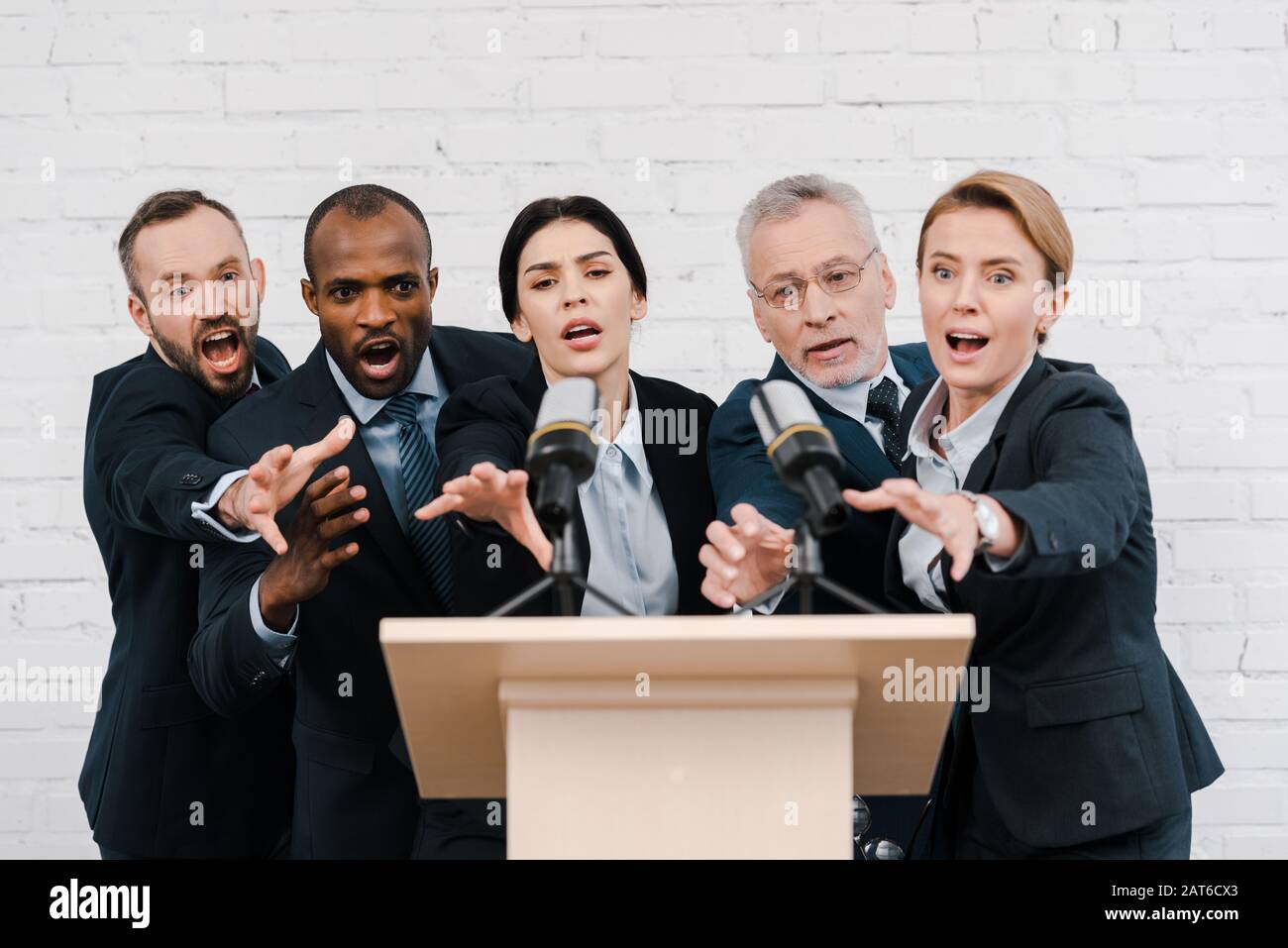 emotional multicultural politics reaching microphones near brick wall ...