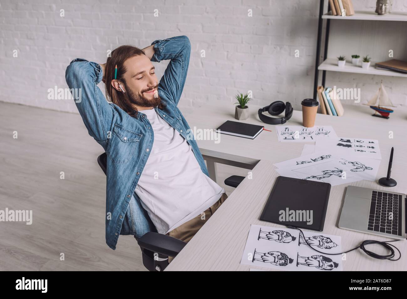 cheerful illustrator smiling near gadgets and sketches Stock Photo