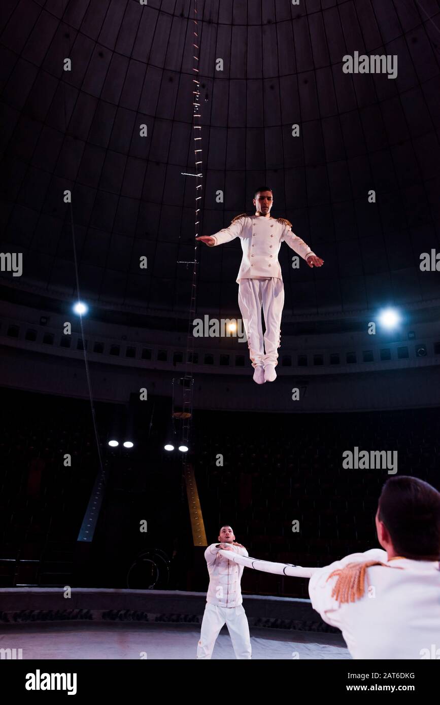 acrobats holding pole while handsome man jumping in circus Stock Photo ...