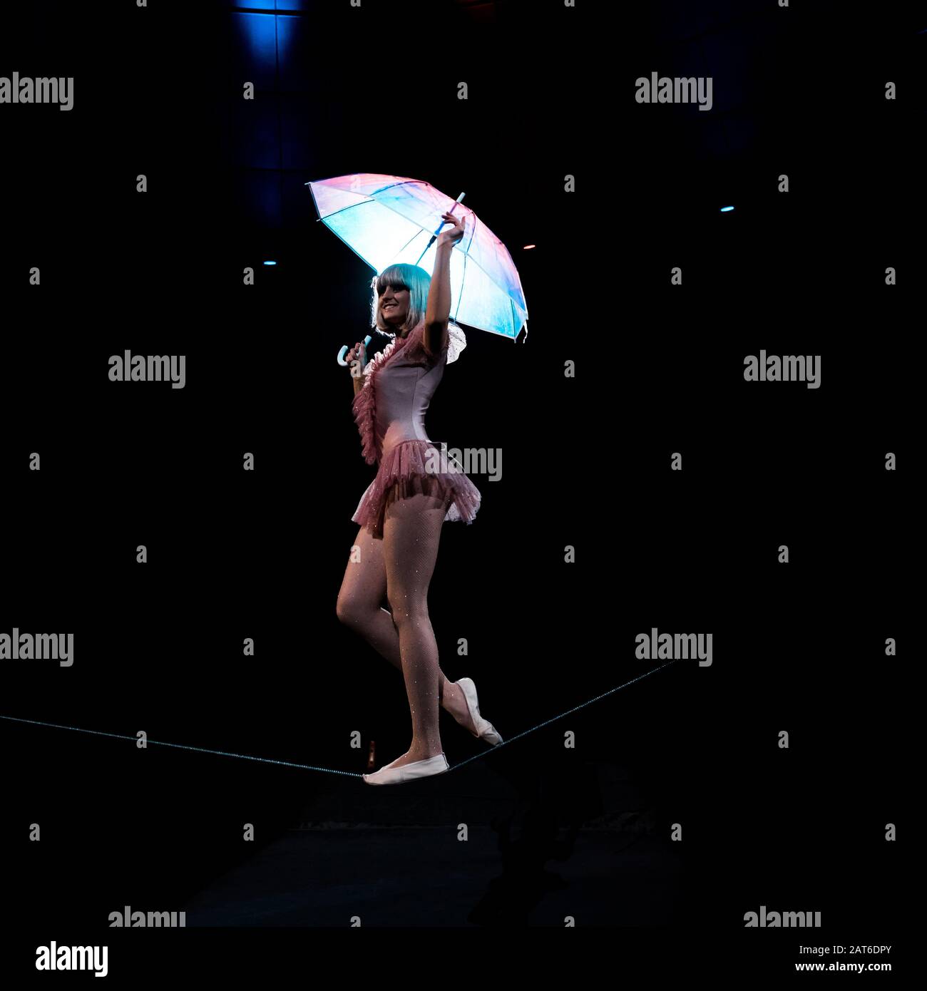 happy acrobat in costume holding umbrella and walking on rope Stock ...