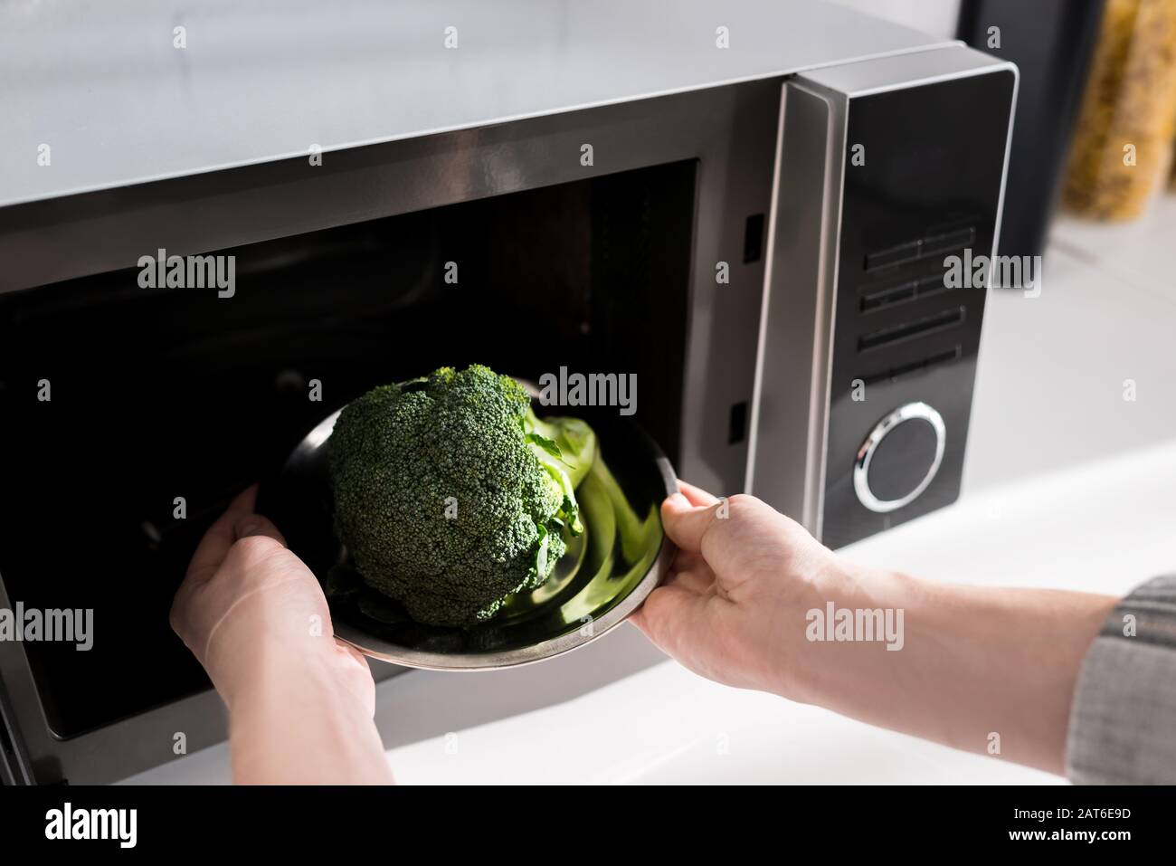 https://c8.alamy.com/comp/2AT6E9D/cropped-view-of-woman-holding-plate-with-broccoli-and-putting-it-in-microwave-2AT6E9D.jpg