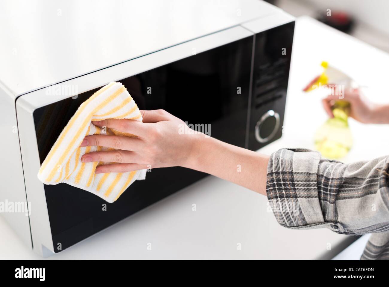 cropped view of woman cleaning microwave with rag in kitchen Stock Photo