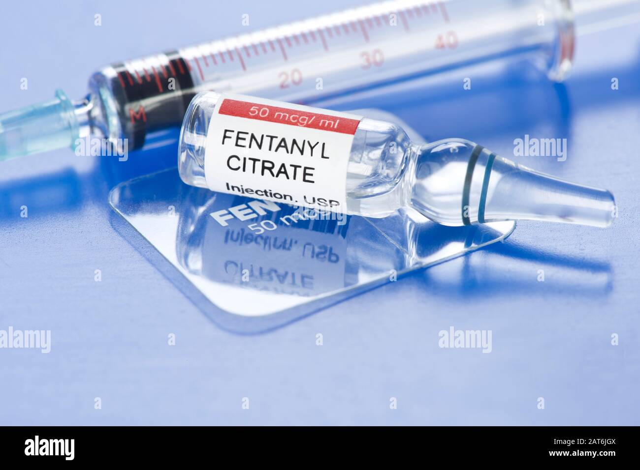 Fentanyl citrate injection ampule with clear fentanyl dermal patch and syringe on blue tray. Stock Photo