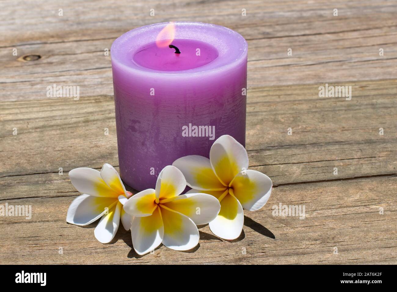 Burning candle on timber deck. Stock Photo