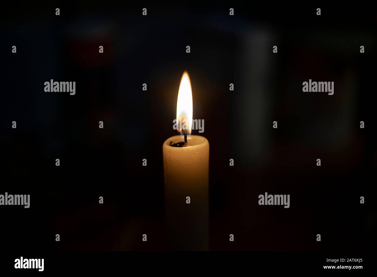 Candle flame in total darkness. A wax candle shines in flame. The wick
