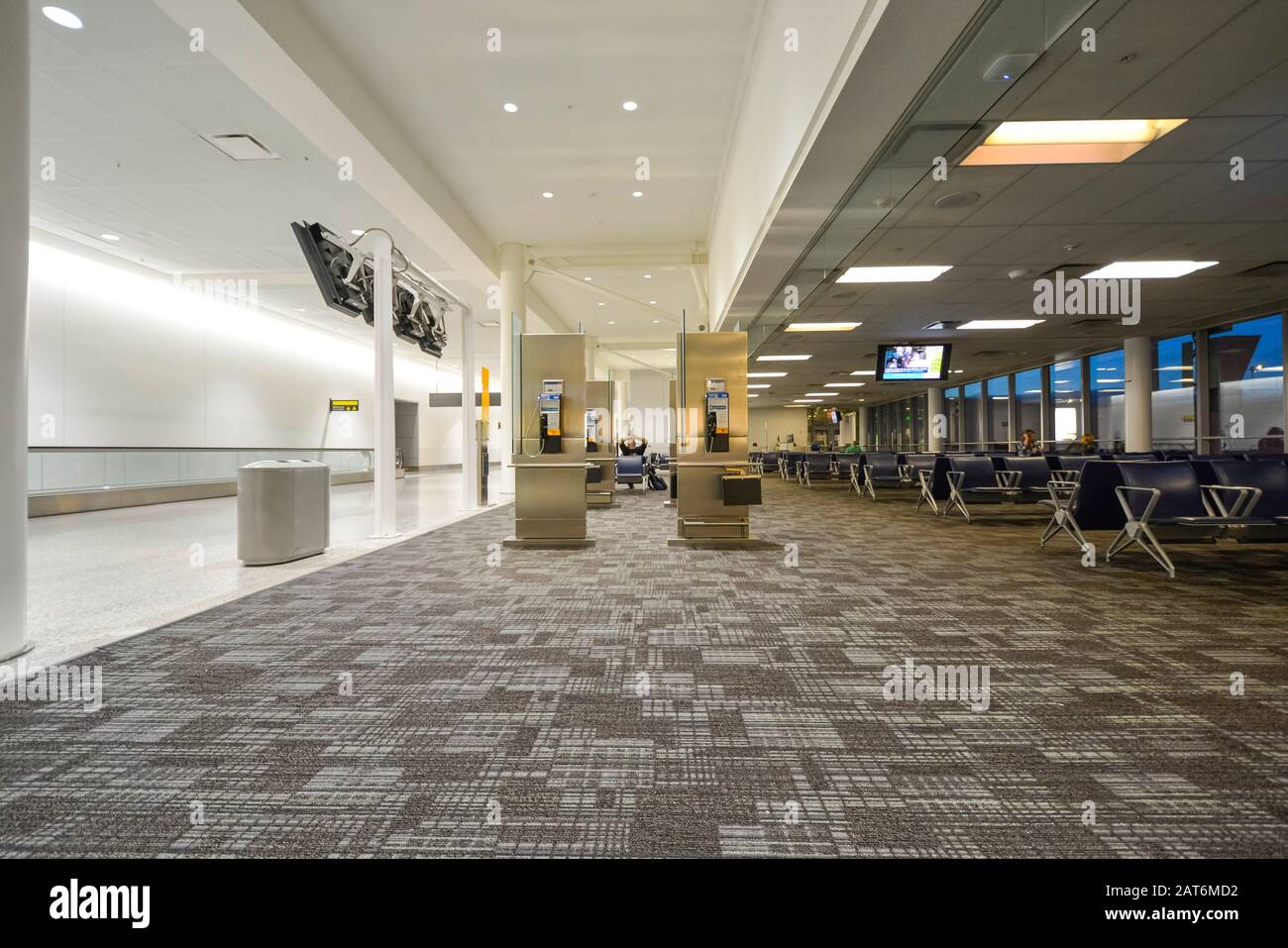 Almost empty airport Terminal early in the morning with very few passengers waiting. Stock Photo