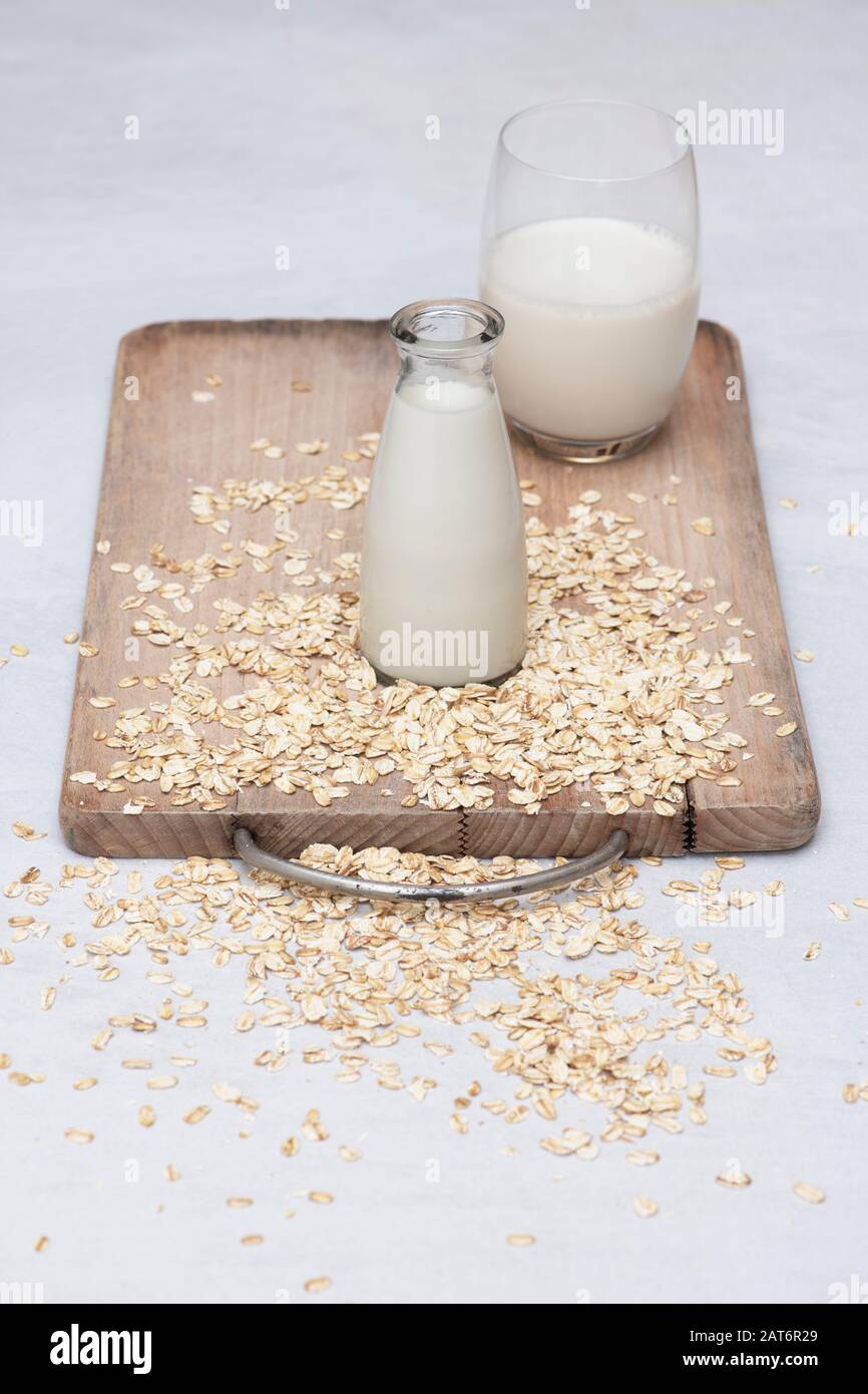 Vegan plant based milk alternatives. Oat Milk and oats on a wooden board Stock Photo