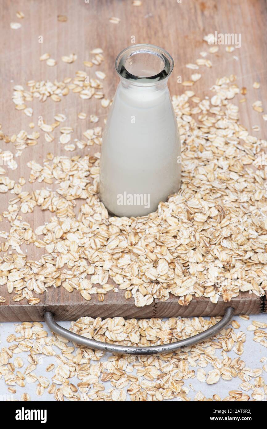 Vegan plant based milk alternatives. Oat Milk and oats on a wooden board Stock Photo
