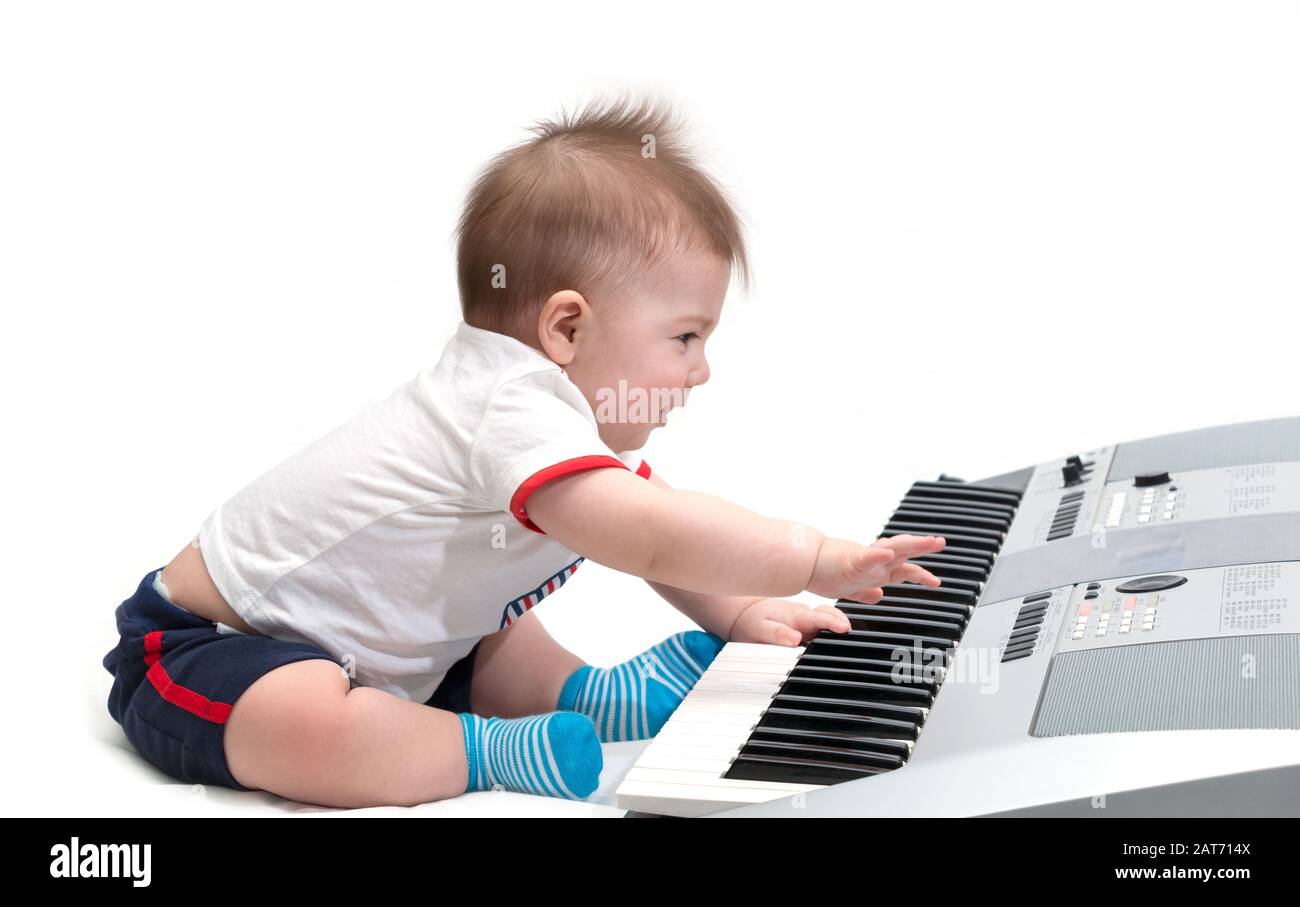 Little baby enjoying playing on piano (synthesizer), isolated on white