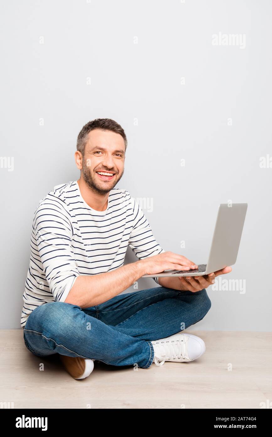 Cheerful happy smiling man sitting on floor with laptop Stock Photo - Alamy