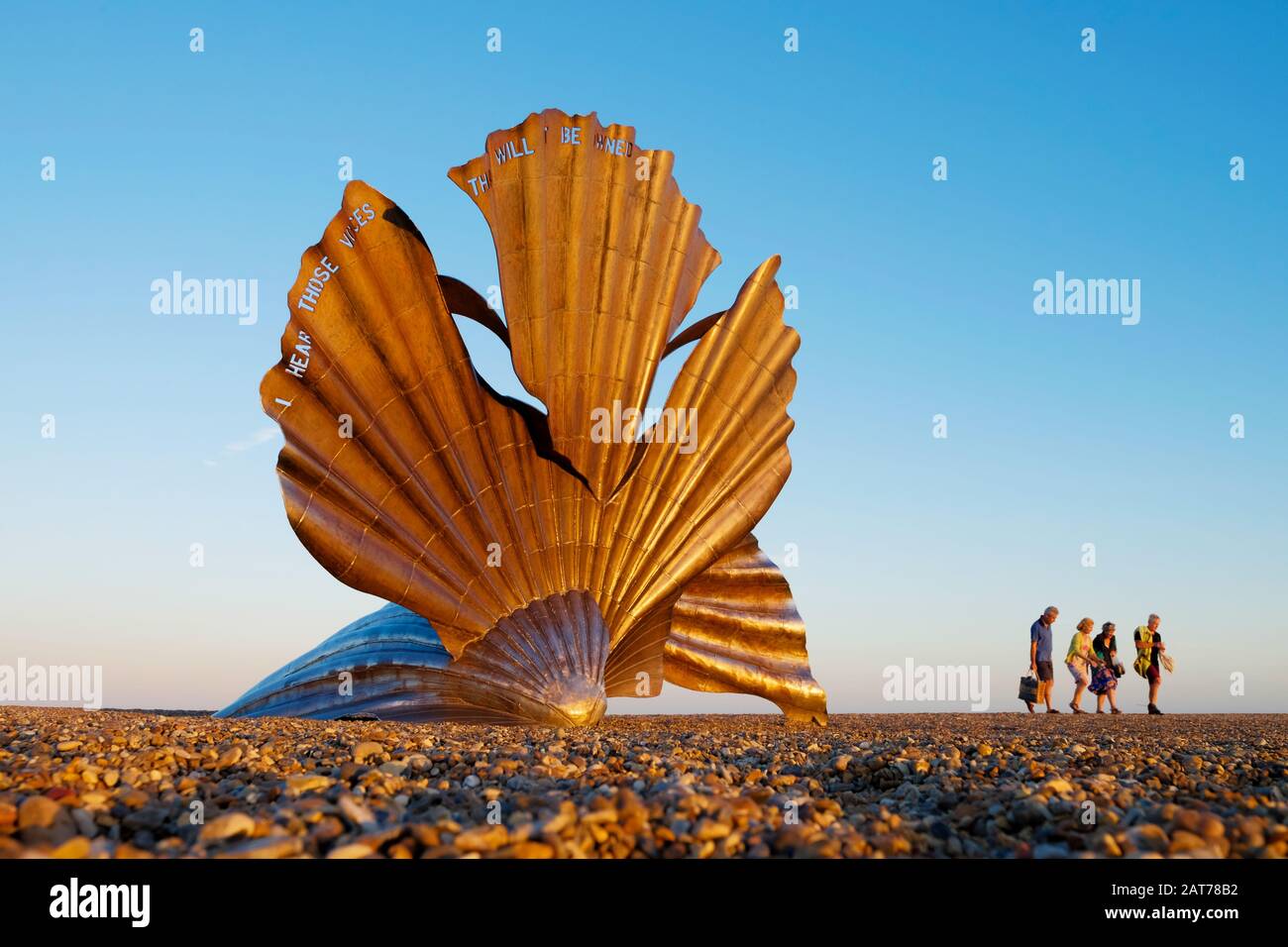 Tourists walking by the Aldeburgh Scallop shell sculpture created by Maggi Hambling. Aldeburgh, Suffolk. UK Stock Photo