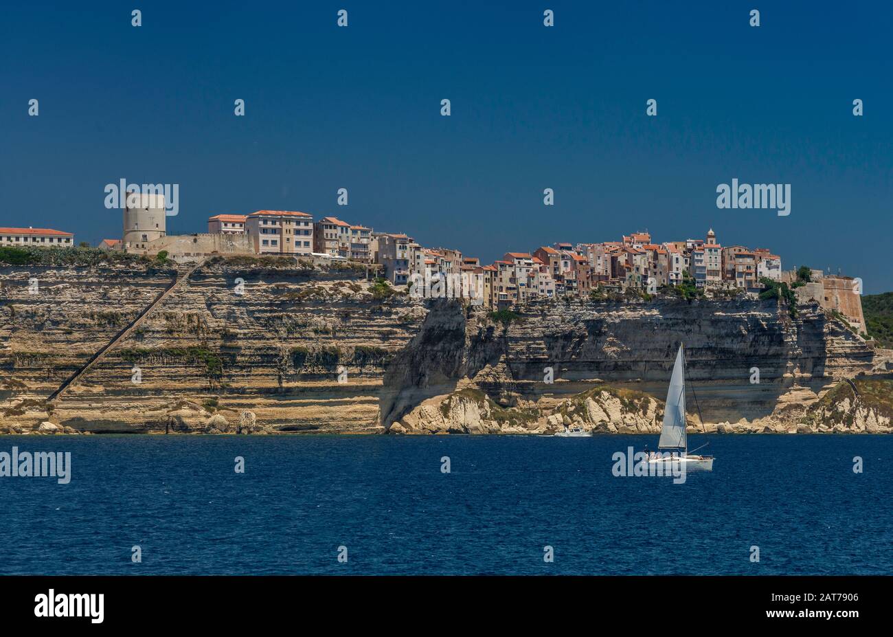 Citadelle on top of limestone cliffs, seen from the sea, King Aragon Steps on left, sailboat, Bonifacio, Corse-du-Sud, Corsica, France Stock Photo