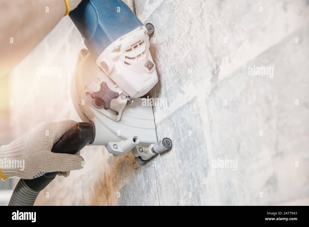 Builder man cutting electrical chase in concrete wall with circulation ...