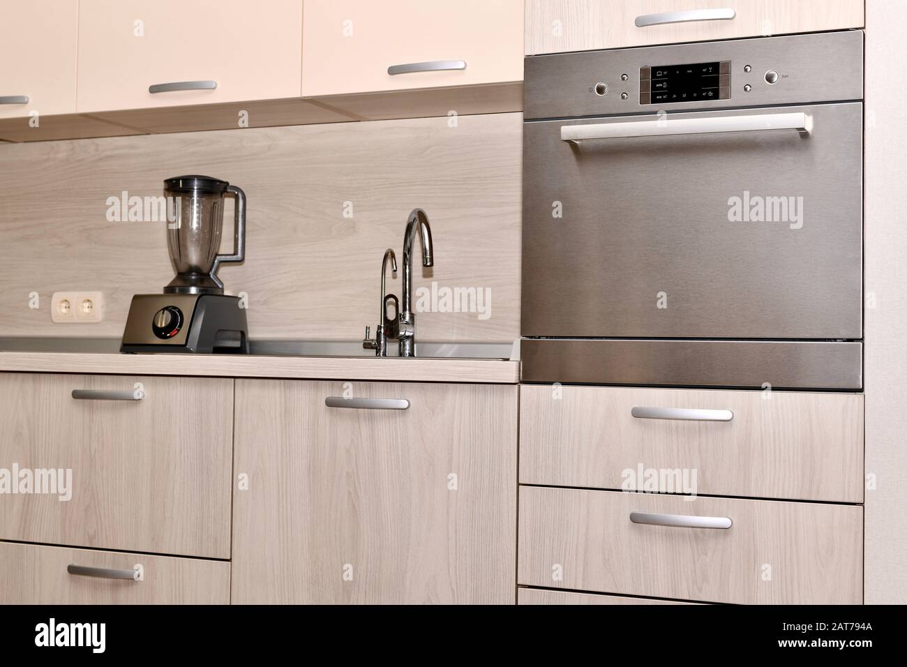 A fragment of kitchen furniture with a dishwasher, conveniently installed at the level of the hostess's belt. Stock Photo