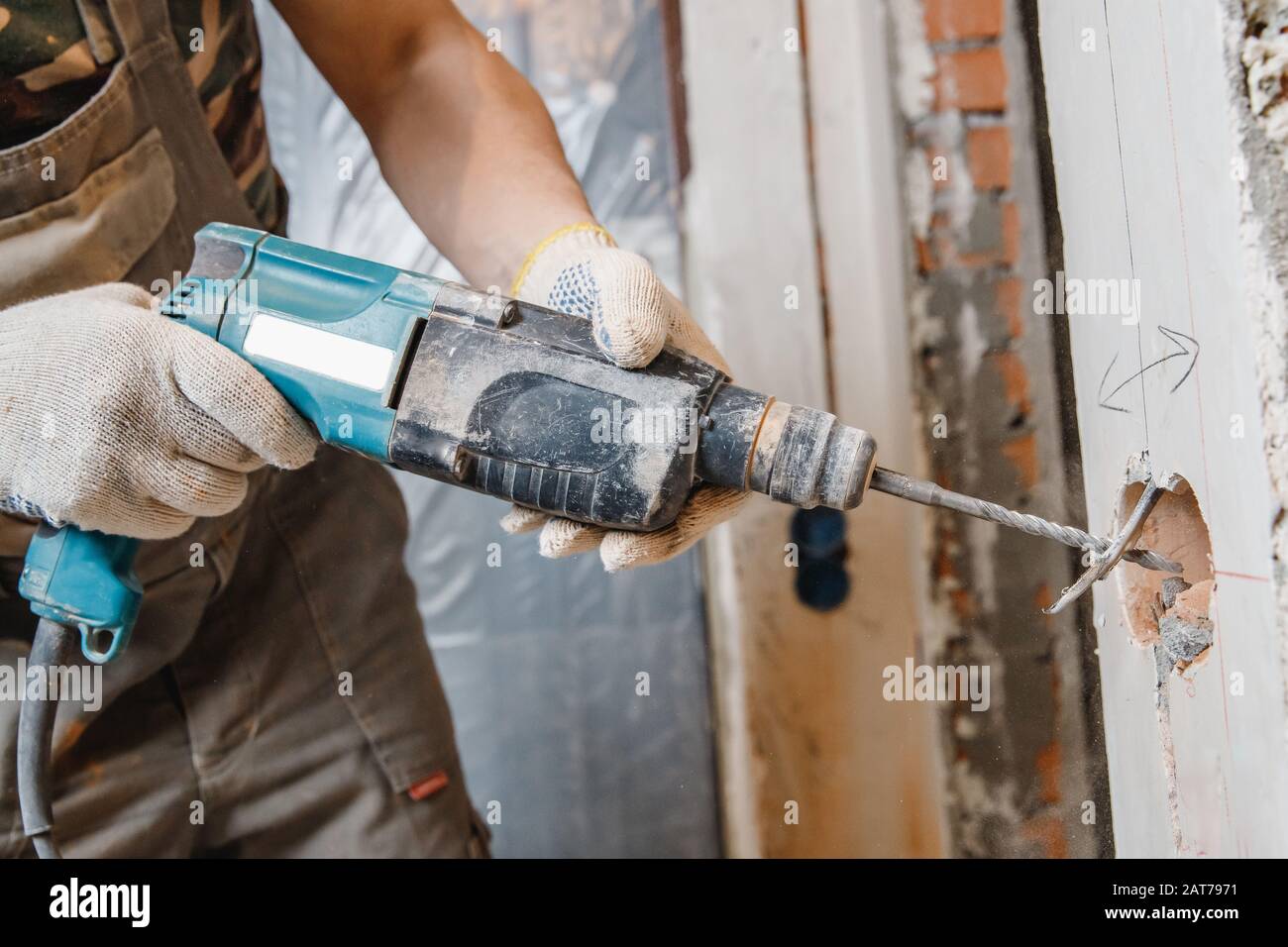 Builder man cutting electrical chase in concrete wall with hammer drill ...