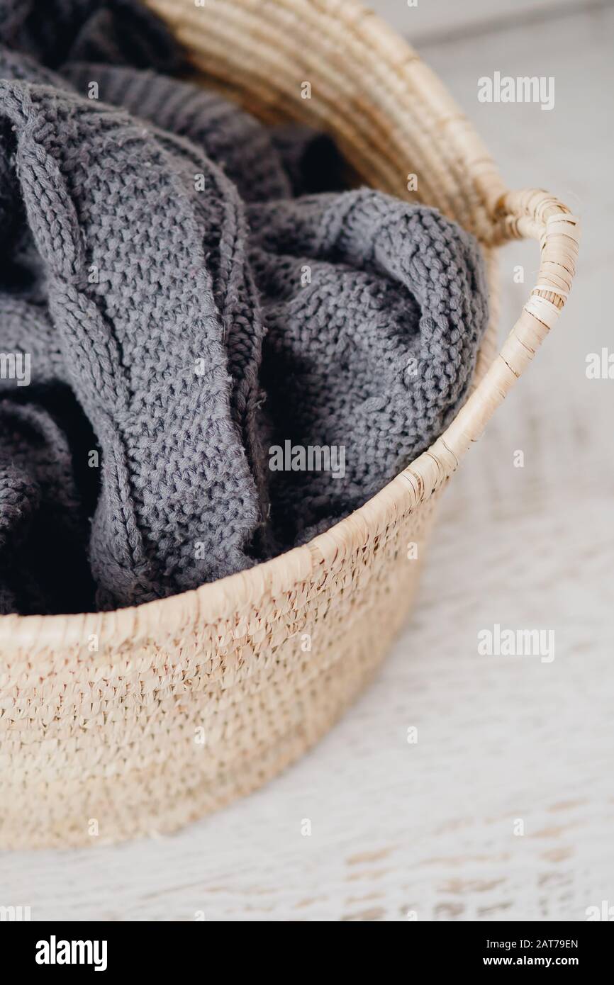 Scandinavian straw laundry basket with blanket on white parquet Stock
