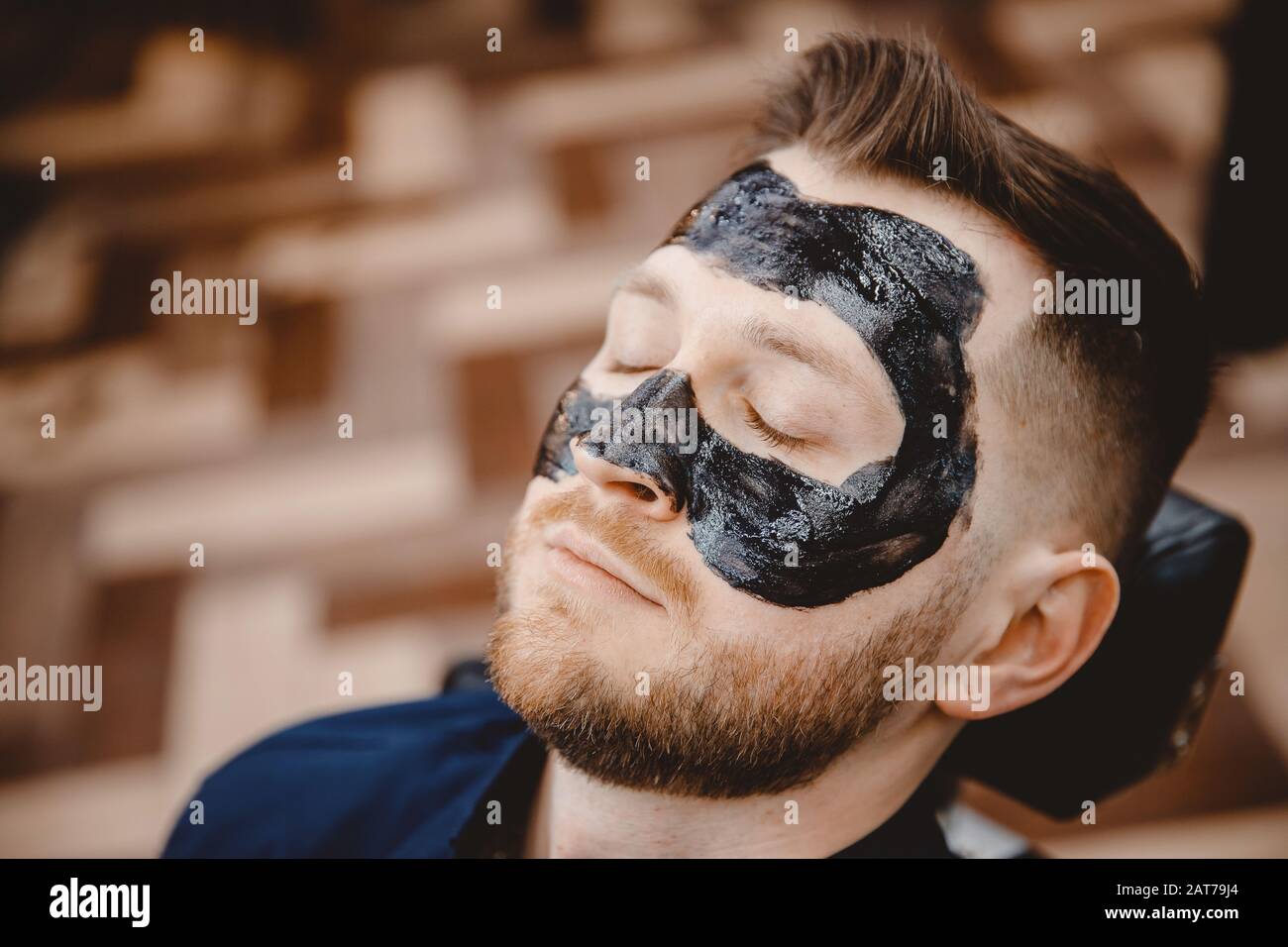 Spa facial skin care for men, applying removal of black charcoal mask from nose face in barbershop Stock Photo