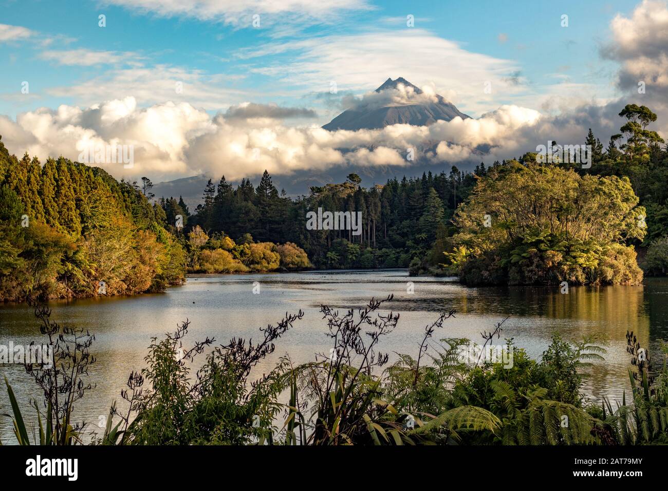 Scenic view on Mount Taranaki (Mount Egmont) in beautiful clouds over a forest and a lake. New Zealand, North Island Stock Photo