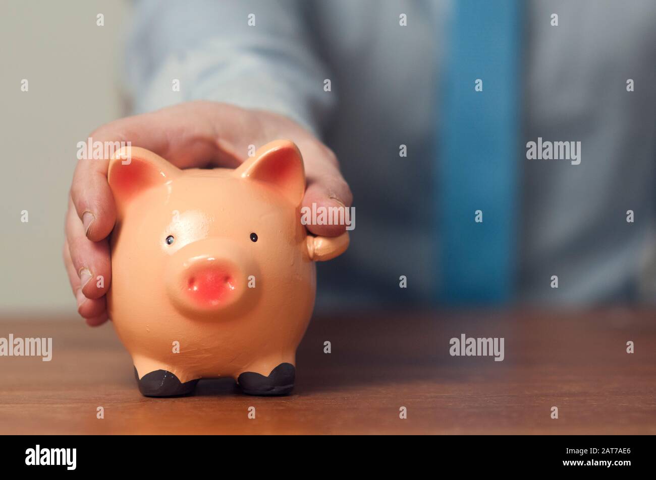 Saving concept: businessman in shirt and tie hold a piggy bank under ...