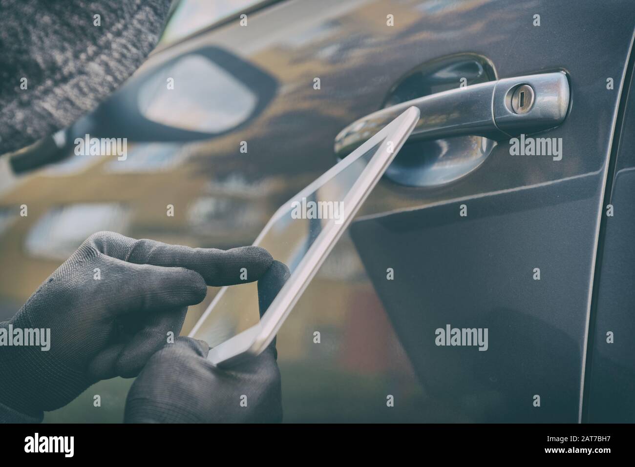 Hooded thief tries to break the car's security systems with tablet