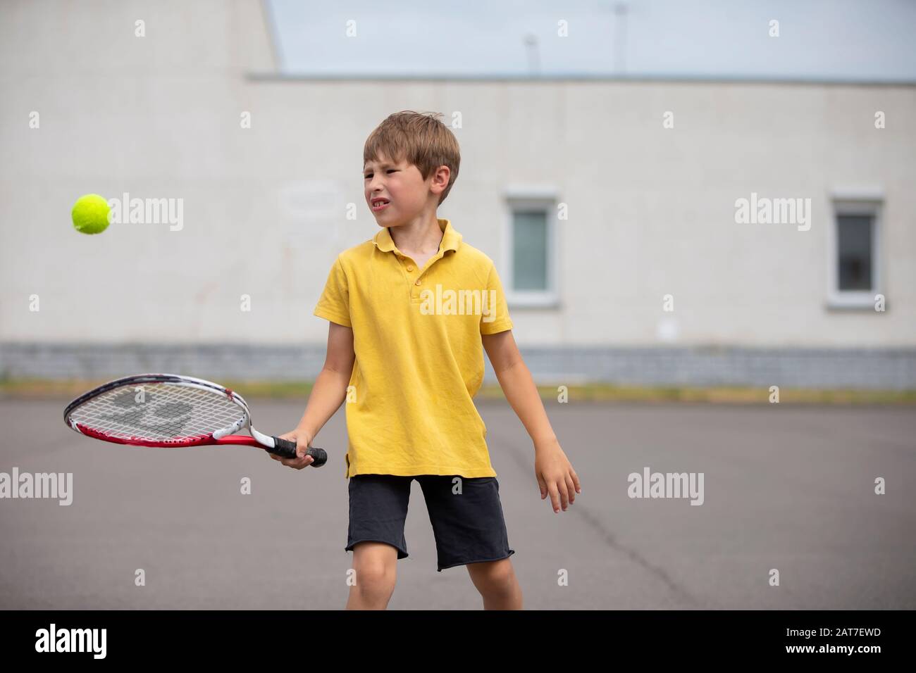 Child with a tennis racket and a ball. Boy tennis player. Schoolboy