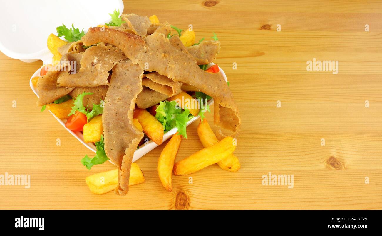 Take away kebab meat and chips with salad in an open fast food box