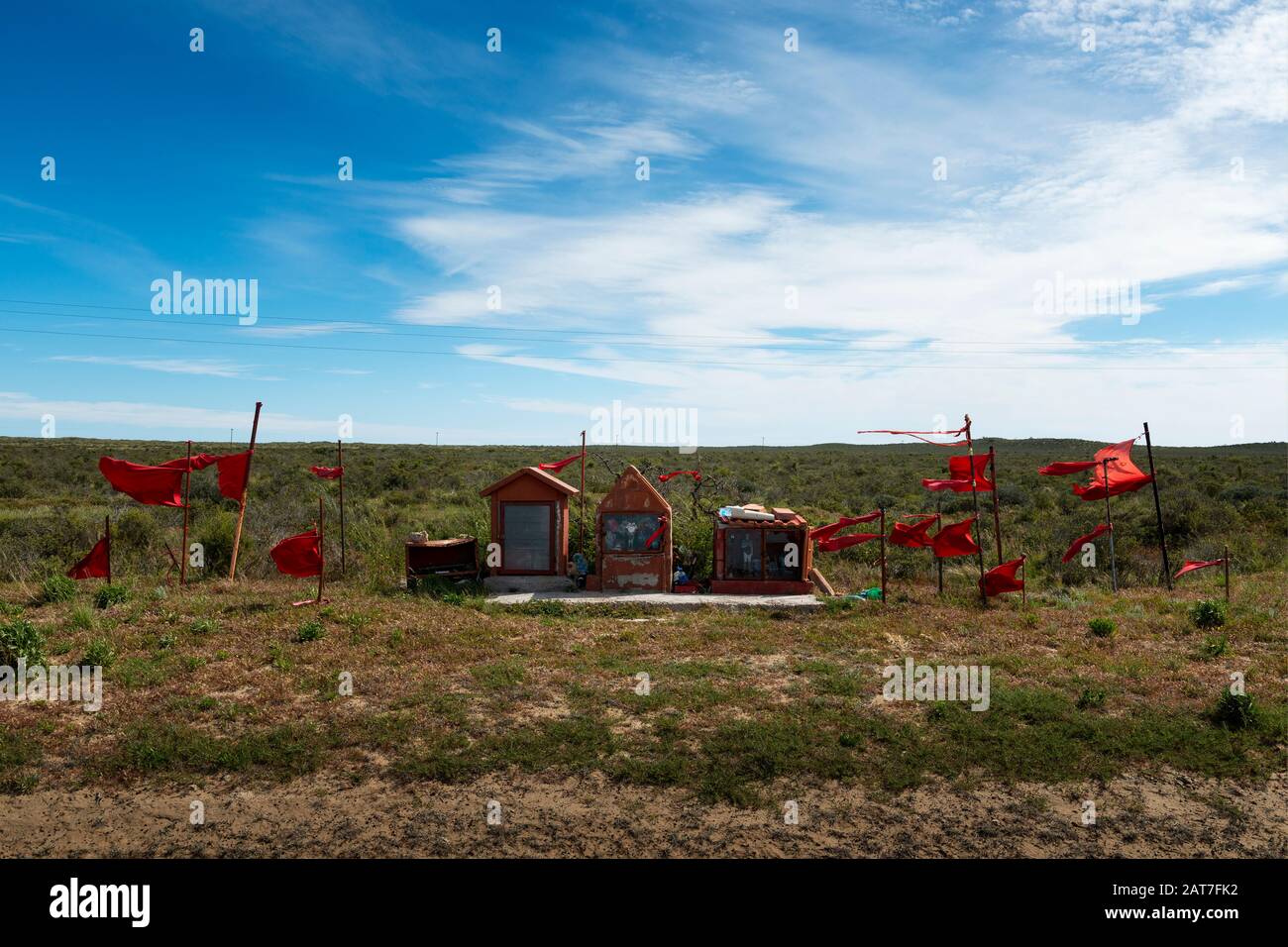 A Guachito Gil shrine with red flags along a road at the Valdes Peninsula in Argentina, South America. Stock Photo