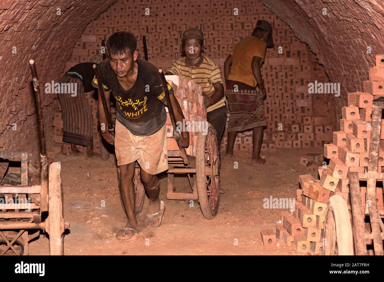 Workers transport fired bricks inside a ring kiln of a brick factory near Luang Prabang, Laos Stock Photo