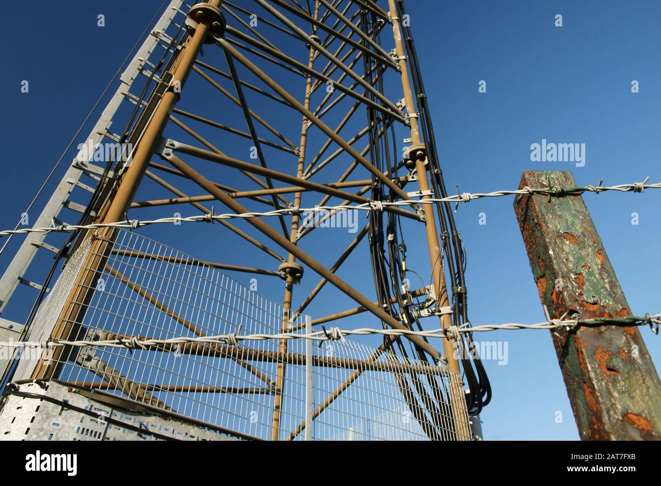 Barbed wire security fence around a mobile and telecommunications transmitter tower Stock Photo