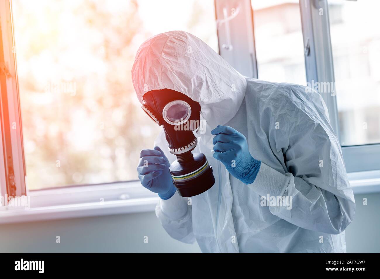 Man wearing protective biological suit and gas-mask due to mers coronavirus global pandemic warning and danger. Medic sphysician scientist make Stock Photo