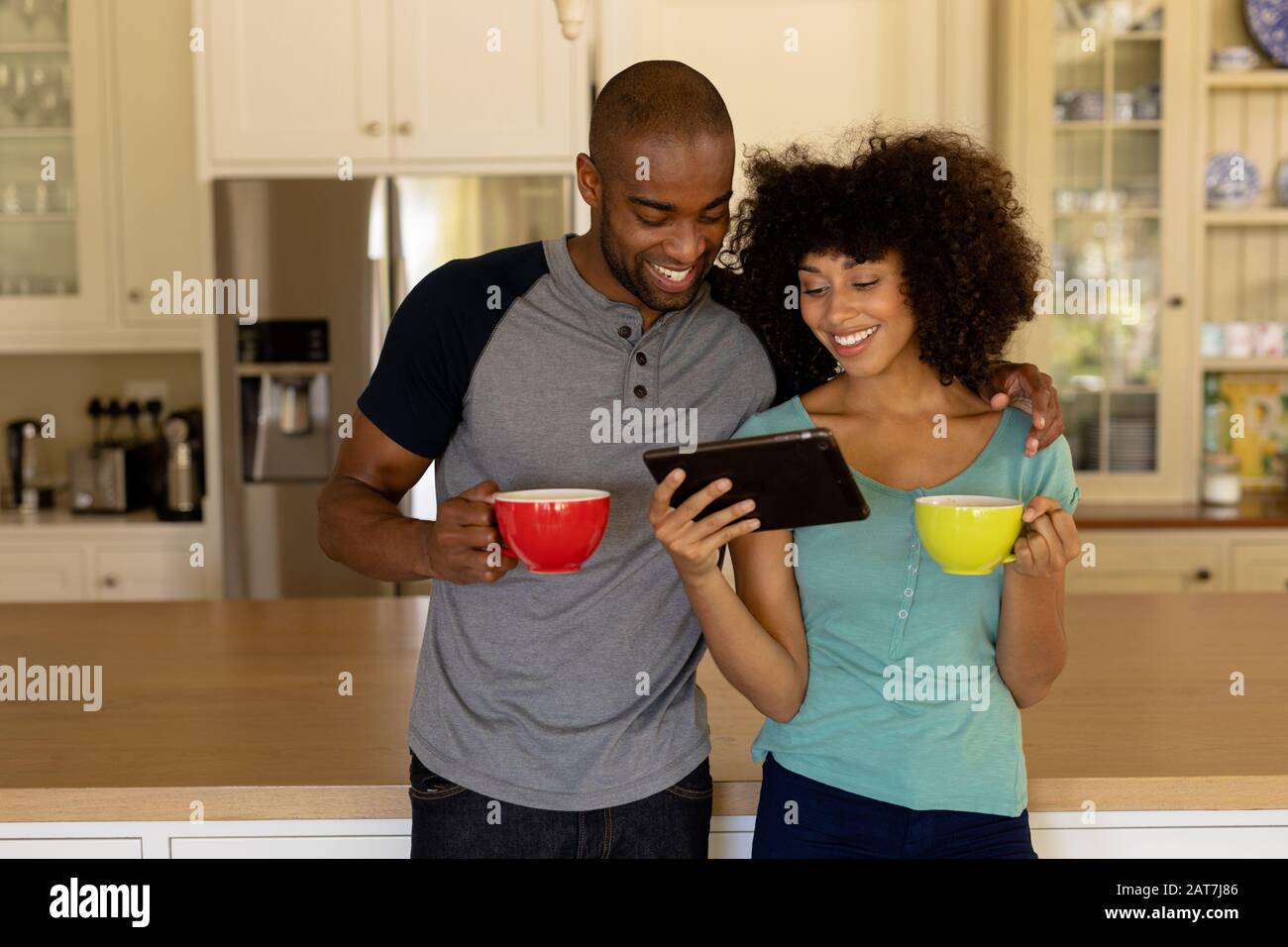 Happy young couple using tablet computer in the kitchen Stock Photo