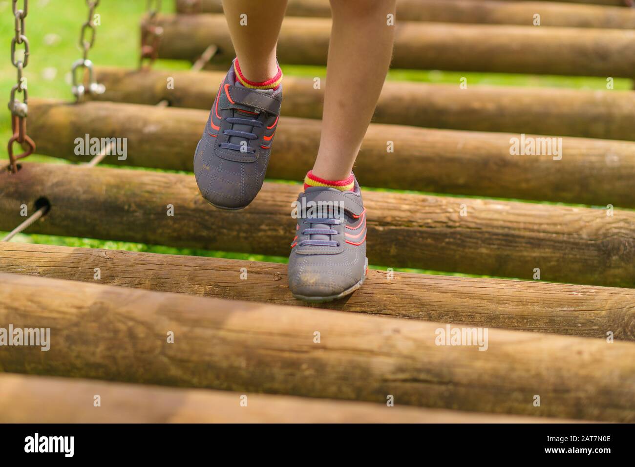 Child balancing along a wobbly bridge on an obstacle course Stock Photo