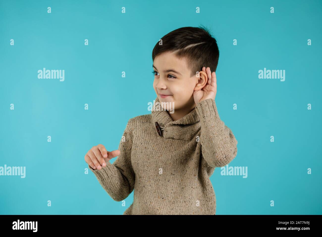 happy little child boy making hearing gesture on blue background. facial expression. kid with hand over ear listening gossip. Stock Photo
