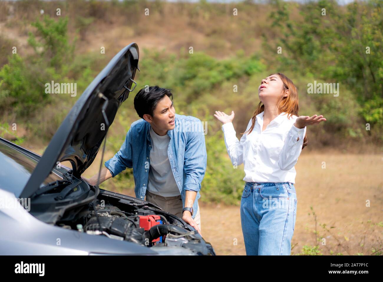 Asian young couple with man and woman on the road having problem breakdown down car engine on the road and woman looking stress when a man can not rep Stock Photo