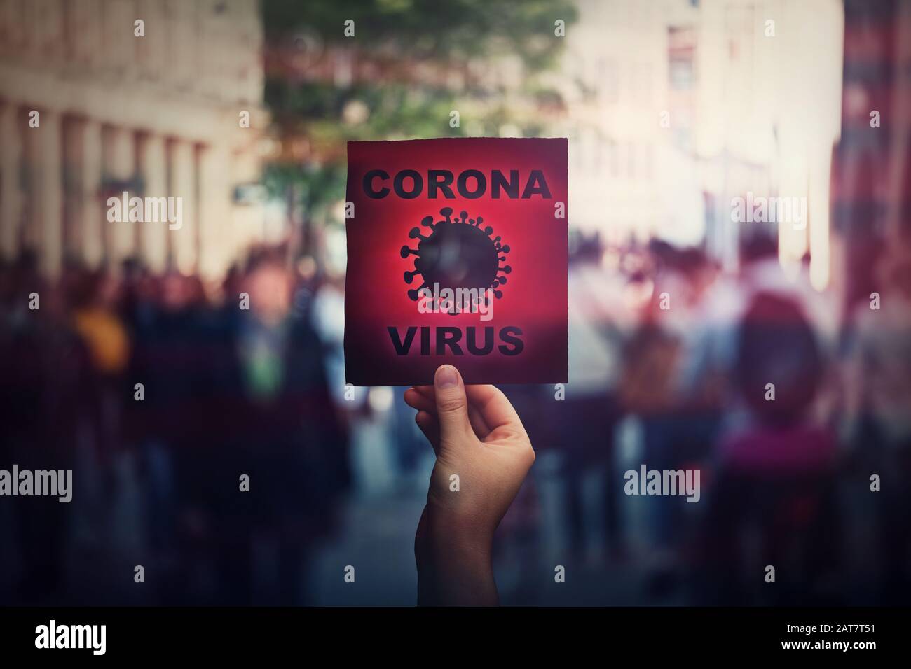 Hand holds red banner warning rapidly spreading Coronavirus on crowded city streets. Deadly Corona virus epidemic outbreak, unknown influenza, fever o Stock Photo