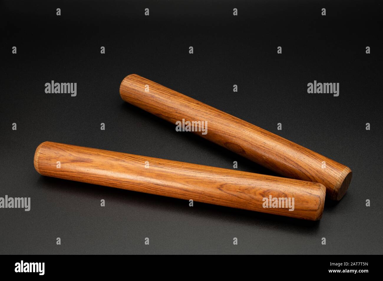Closeup of a pair of wooden claves lying on a black underground Stock Photo
