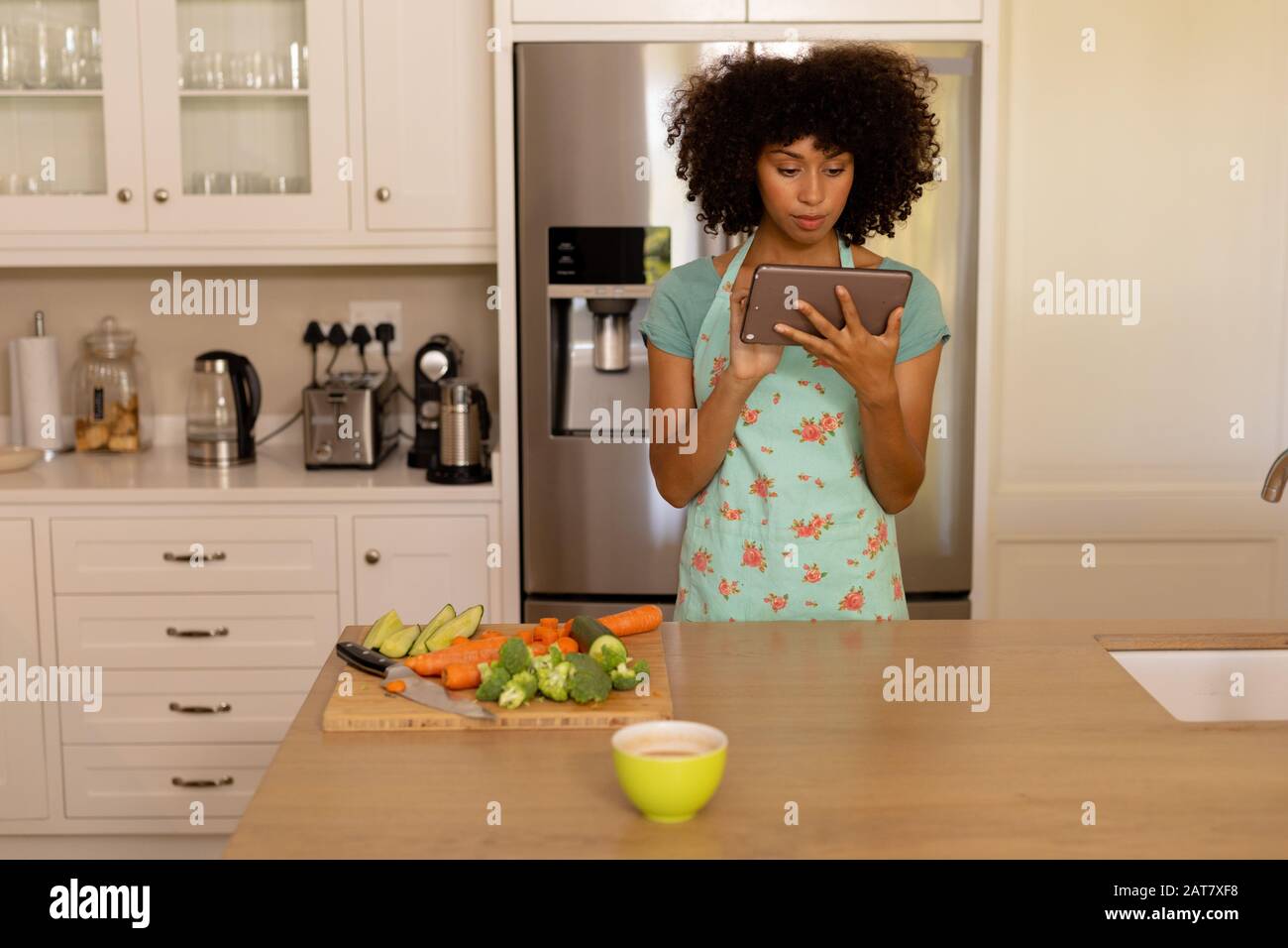 Young woman using tablet computer in the kitchen Stock Photo
