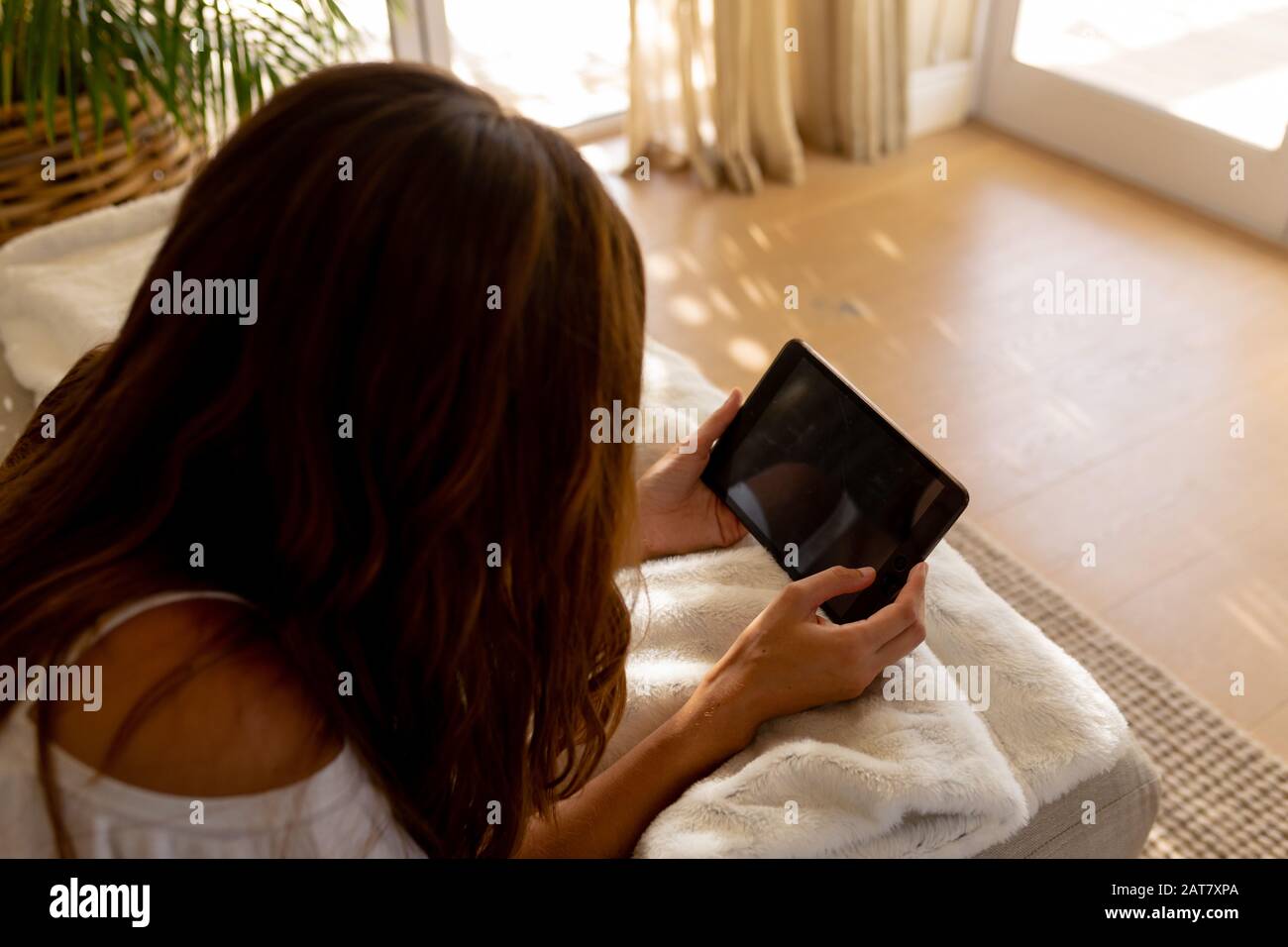 Young woman using tablet computer on sofa at home Stock Photo