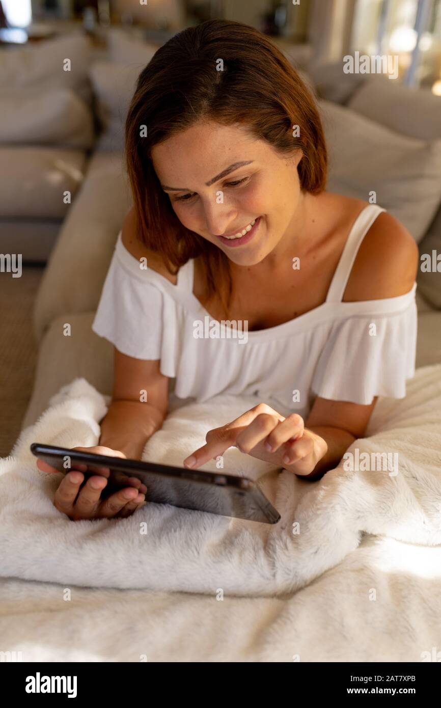 Young woman using tablet computer on sofa at home Stock Photo